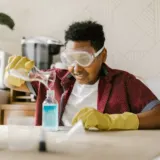 Boy in safety goggles pouring liquid into a bottle during a science experiment