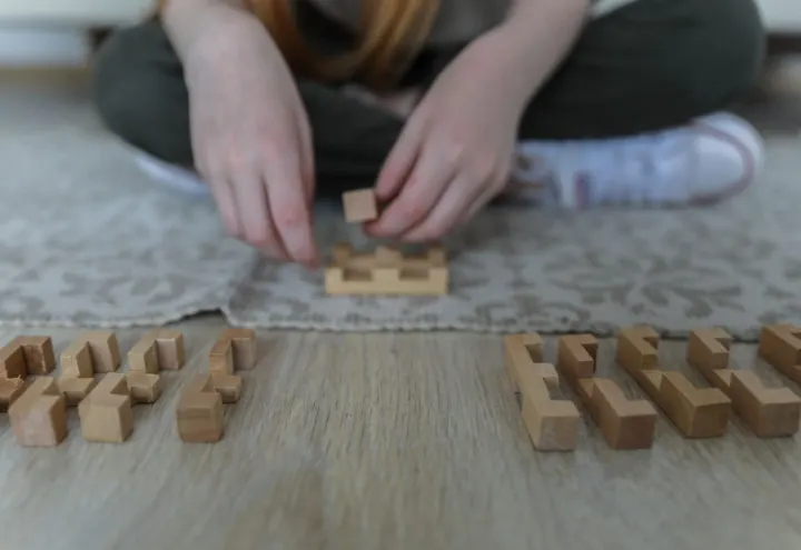 Child sitting cross-legged on a rug fitting together small wooden building blocks