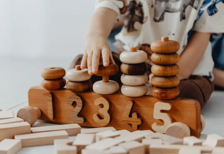 Child stacking wooden rings onto a numbered one-to-five wooden counting toy
