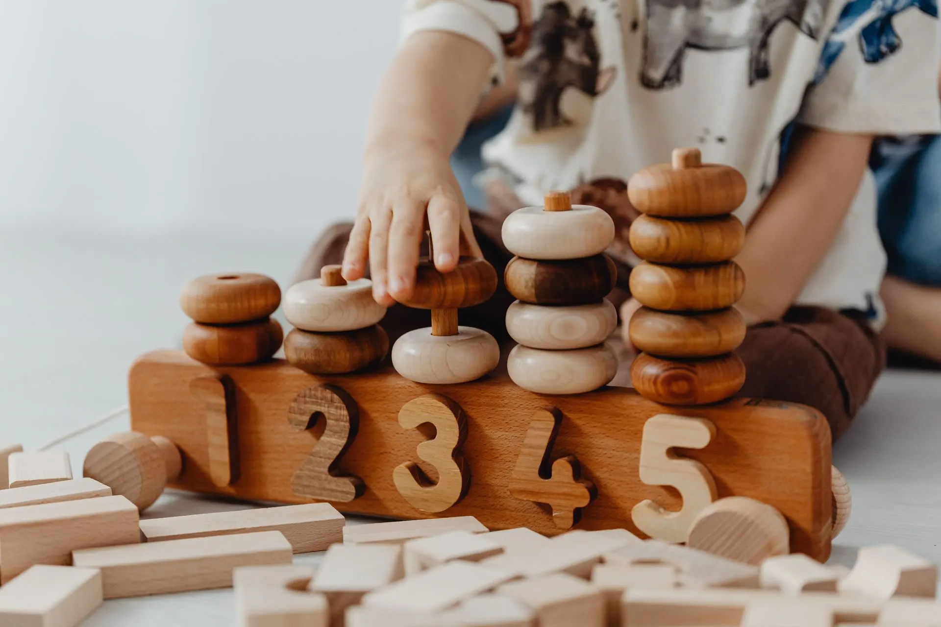 Child stacking wooden rings onto a numbered one-to-five wooden counting toy