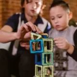 Father and son building a tower from colorful magnetic tiles at home