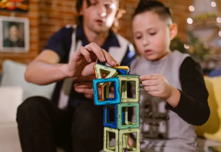 Father and son building a tower from colorful magnetic tiles at home
