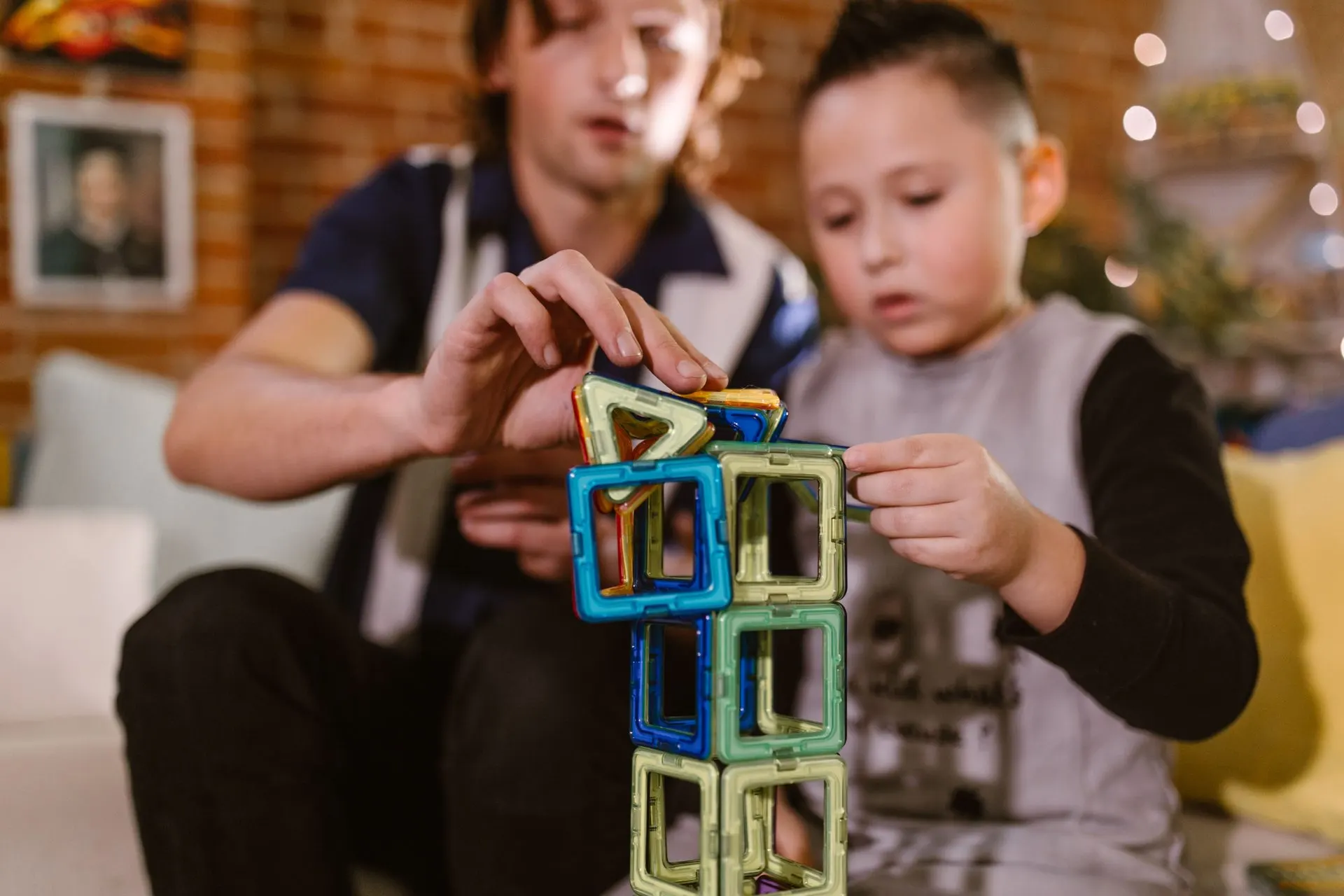 Father and son building a tower from colorful magnetic tiles at home